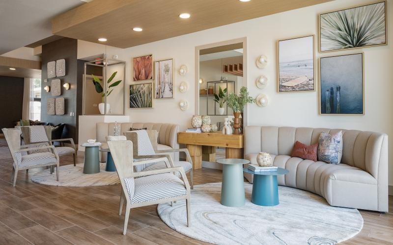 a clubhouse with couches, chairs, tables and wall art